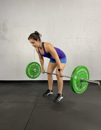 woman halfway up on a deadlift with a barbell